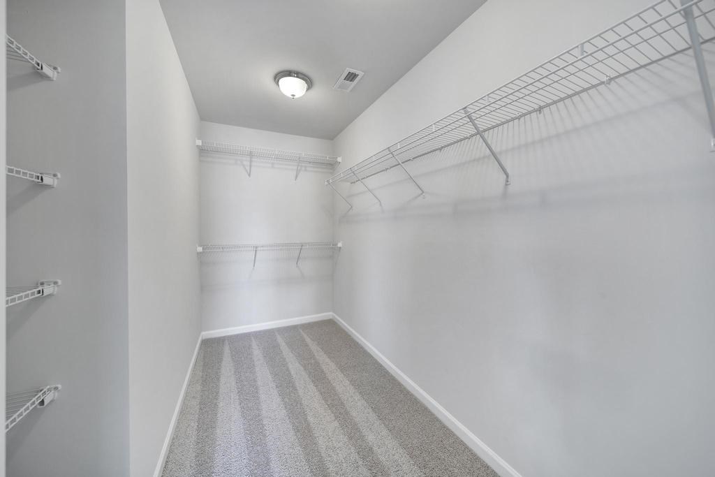 A long, narrow hallway with striped carpeting and white walls.