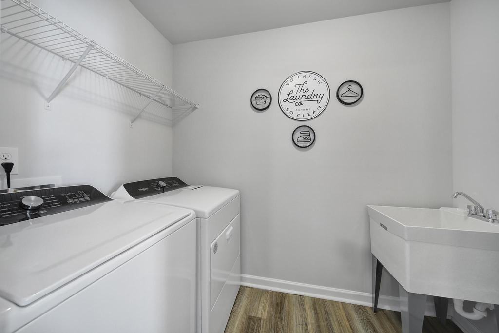 A laundry room with a washer and dryer, sink, and wall decor.
