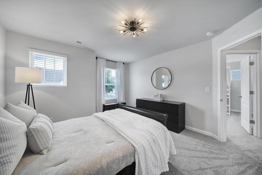 A bedroom with a large bed and a window with blinds.
