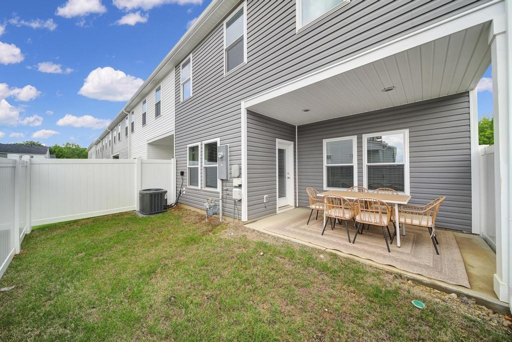 A grey house with a white fence and a small patio.
