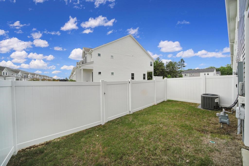 A white fence encloses a yard with a house in the background.