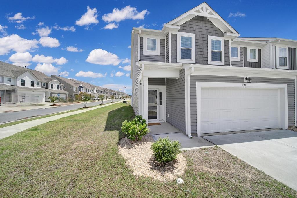 A grey house with a white garage door is in front of a row of houses.