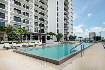 Apartments Miami FL - MB Station - Apartment Balconies Overlooking Sparkling Resort-Style Pool Surrounded by Lounge Seating - Photo Gallery 5