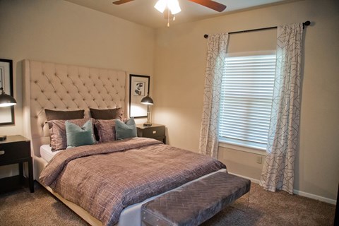 A bedroom with a large bed and a ceiling fan.