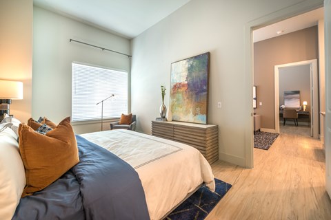 A bedroom with a large bed and a painting on the wall.