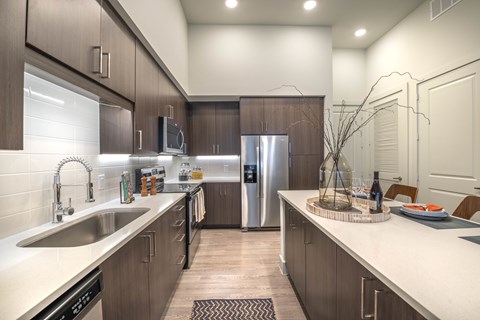 A modern kitchen with dark wood cabinets and stainless steel appliances.