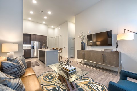 A modern living room with a glass coffee table and a brown leather couch.