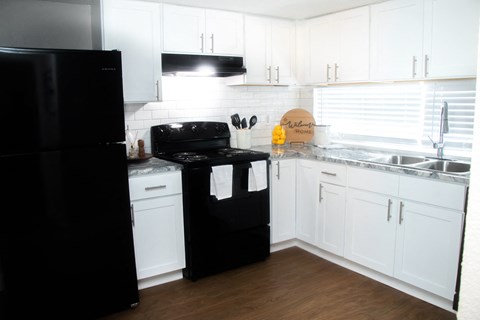 a kitchen with white cabinets and a black stove and refrigerator
