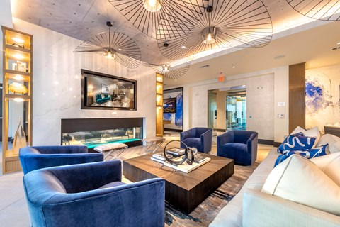 A living room with a fireplace, blue chairs, and a painting on the wall.