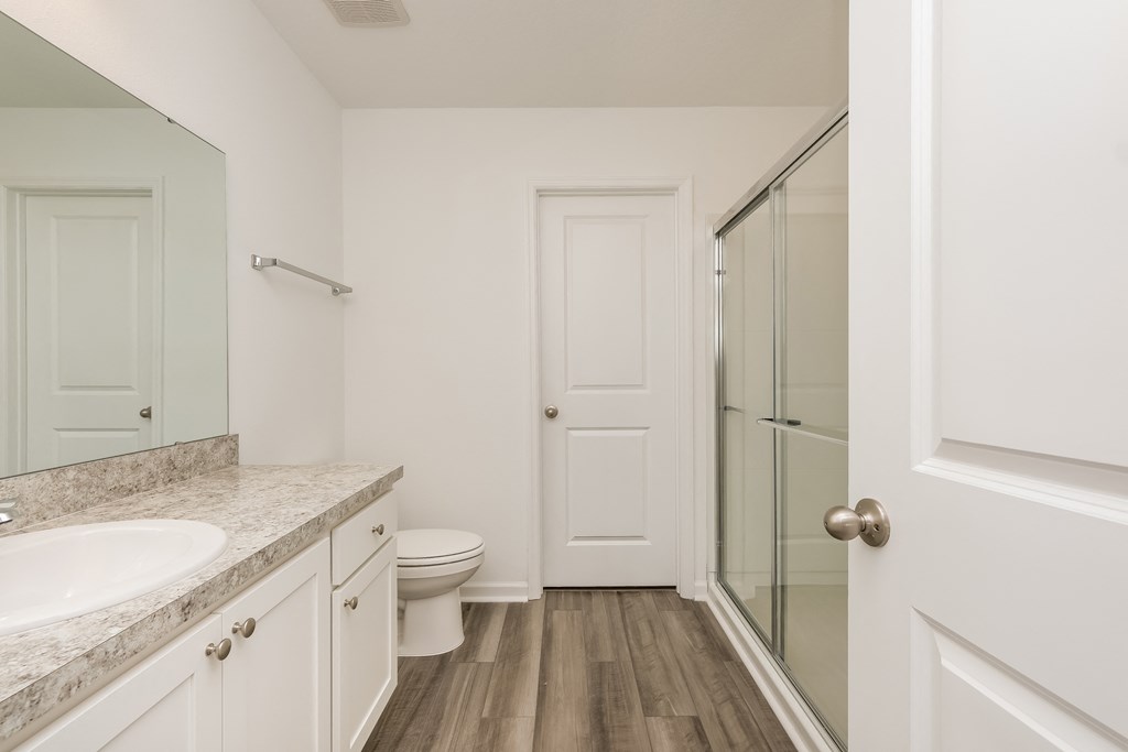 A white bathroom with a sink, toilet and a door.