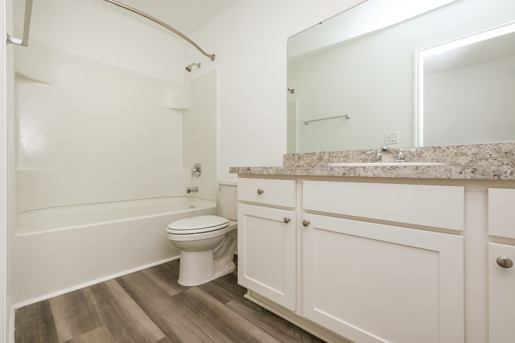 A white toilet sits in a bathroom next to a bathtub.