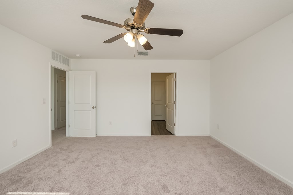 A room with a ceiling fan and carpeted floor.