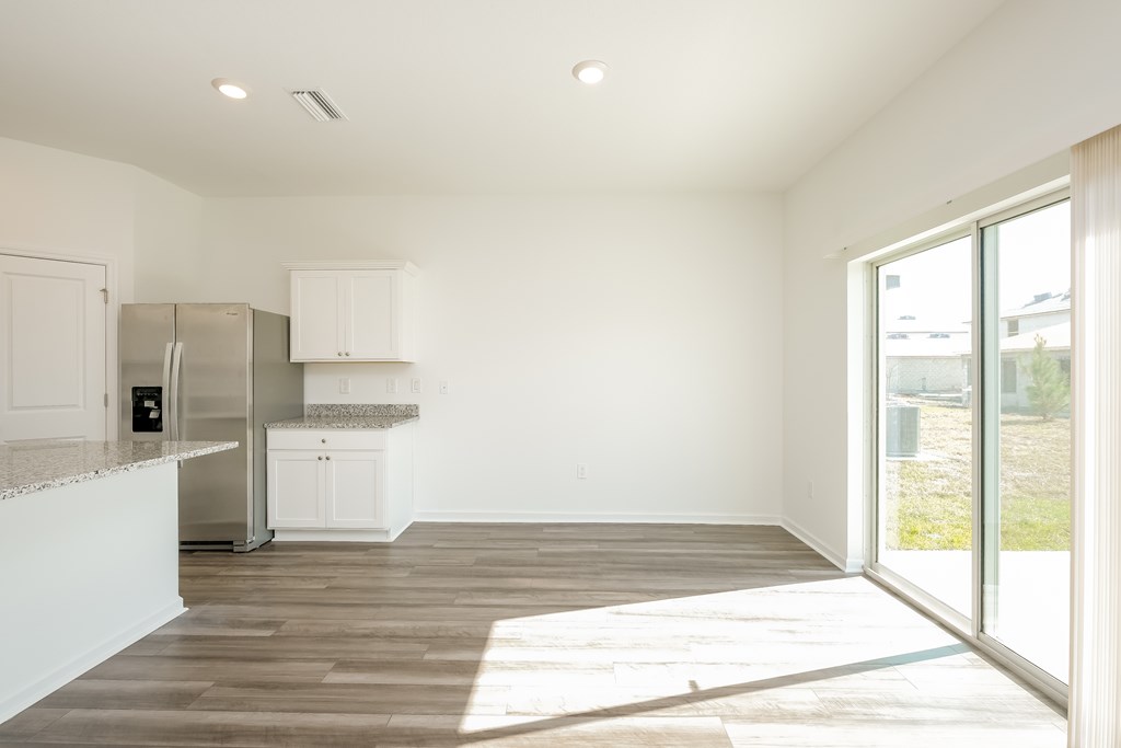 A kitchen with white cabinets and a refrigerator.