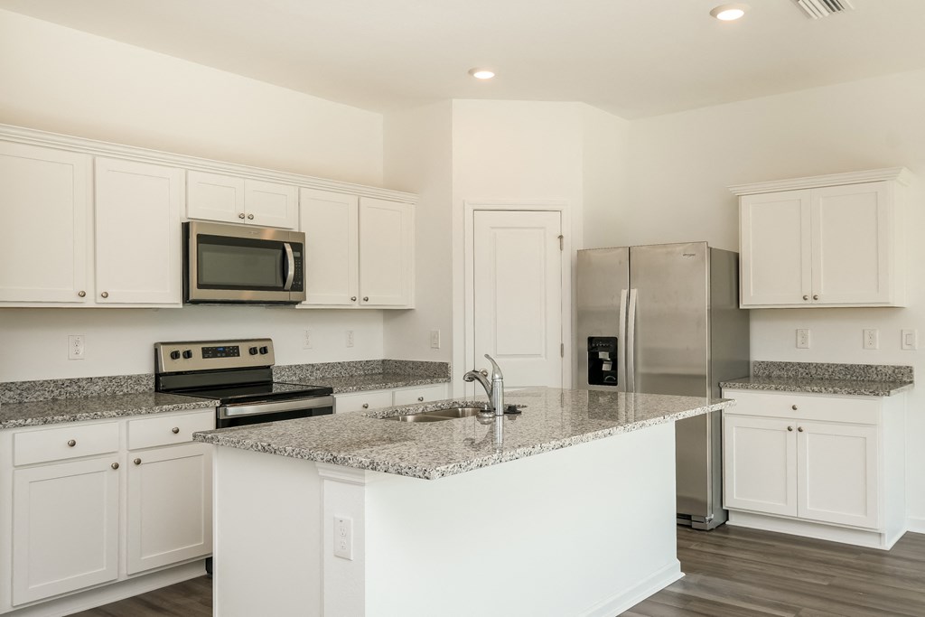 A kitchen with white cabinets and a granite countertop.