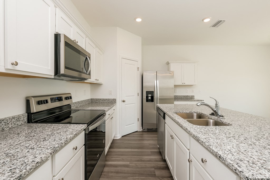 A kitchen with granite countertops and white cabinets.