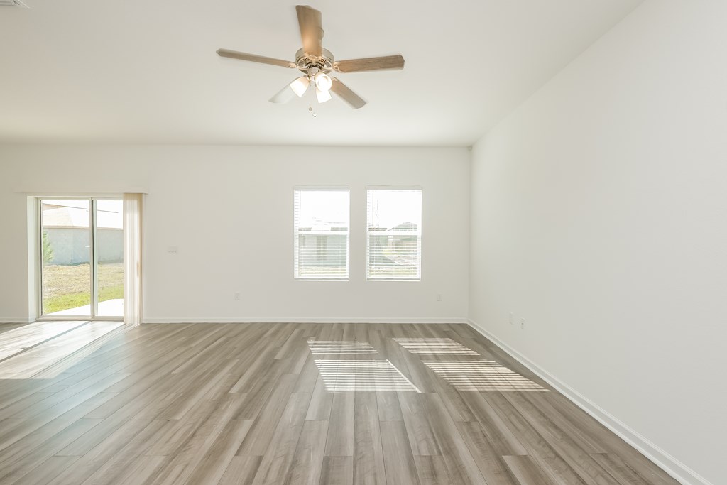 A room with a ceiling fan and wooden flooring.