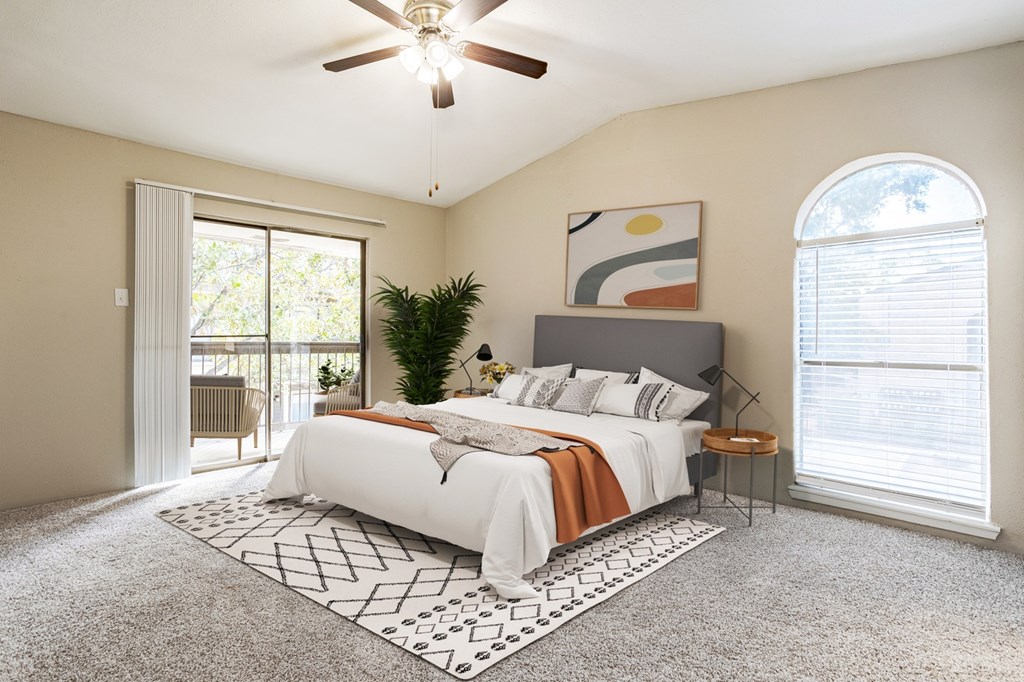 West Houston, TX Apartments – Magnolia Terrace – A bedroom with a large bed and a ceiling fan.