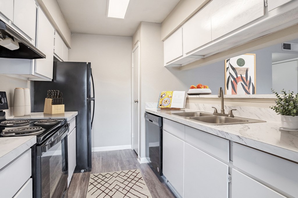 Pet-Friendly Apartments in West Houston, TX– Magnolia Terrace- A kitchen with a black refrigerator and white cabinets.