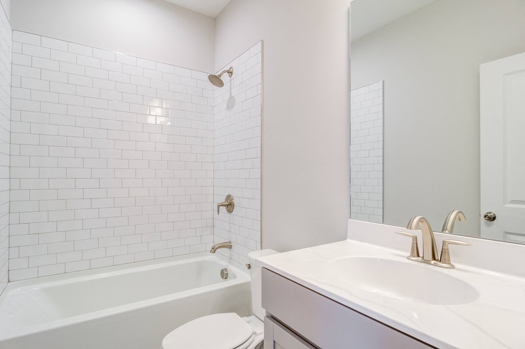 a bathroom with white tiles and a sink and a bath tub