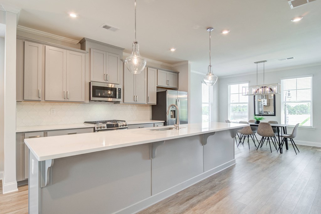 a large white kitchen with a large island and a dining room
