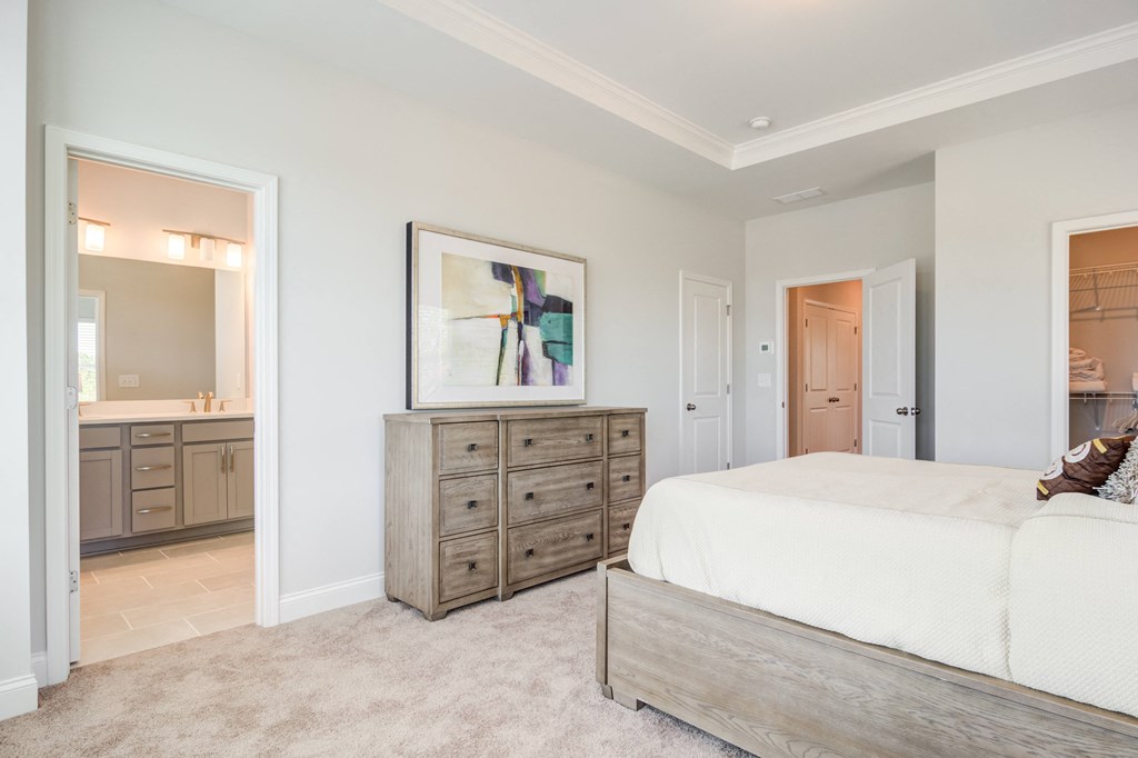 a bedroom with a bed and a dresser and a bathroom