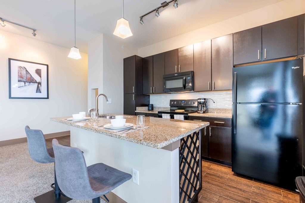 a kitchen with a granite counter top and a stainless steel refrigerator