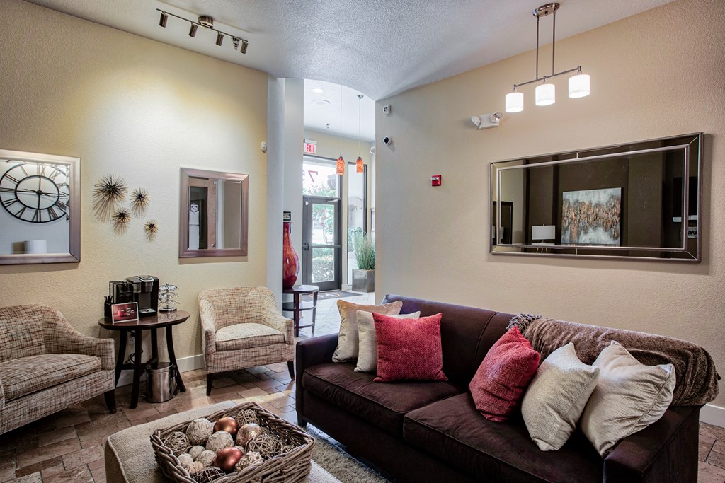The Club house with a couch chairs and a coffee table At Metropolitan Apartments in Little Rock, AR