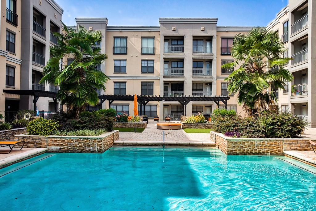 A large swimming pool with umbrellas and cabanas and beach chairs
