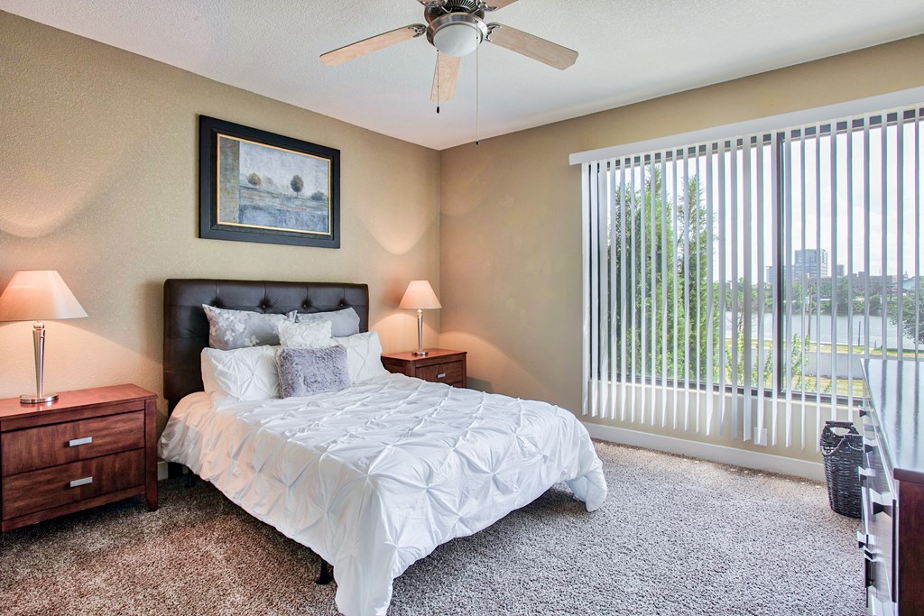 a bedroom with a ceiling fan and glass door with blinds