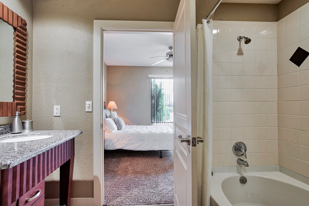 bathroom with tile floors and mirror and bathtub with tile backsplash and cabinets
