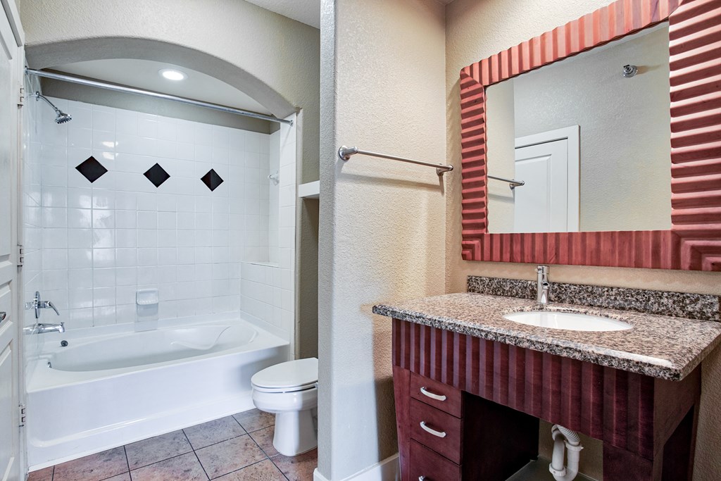 bathroom with tile floors and mirror and bathtub with tile backsplash and cabinets
