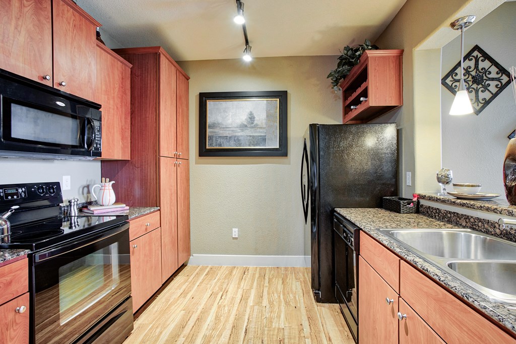 Kitchen with wood flooring and black appliances and wood cabinets and steel sink