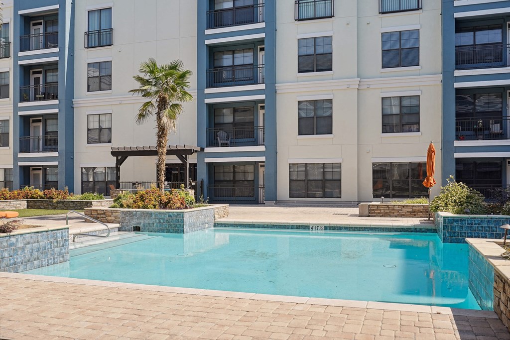 1, 2 -Bedroom Apartments for Rent in North Little Rock, AR – Metropolitan– A pool in front of a building with a palm tree.