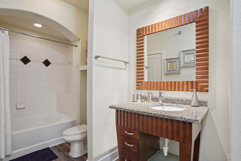 Apartments for Rent in North Little Rock, AR 72114– Metropolitan-   A bathroom with a white tub and a wooden vanity.