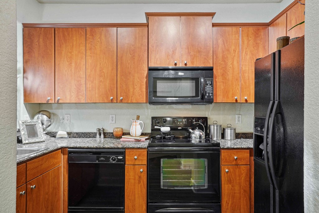 1, 2 -Bedroom Apartments for Rent in North Little Rock, AR – Metropolitan– A kitchen with black appliances and wooden cabinets.