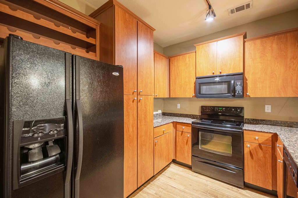 Kitchen with wood flooring and black appliances and wood cabinets and steel sink