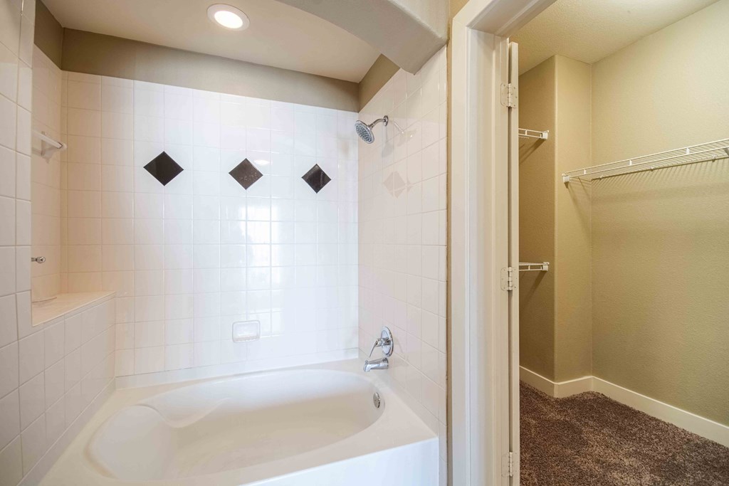 bathroom with tile floors and mirror and bathtub with tile backsplash and cabinets