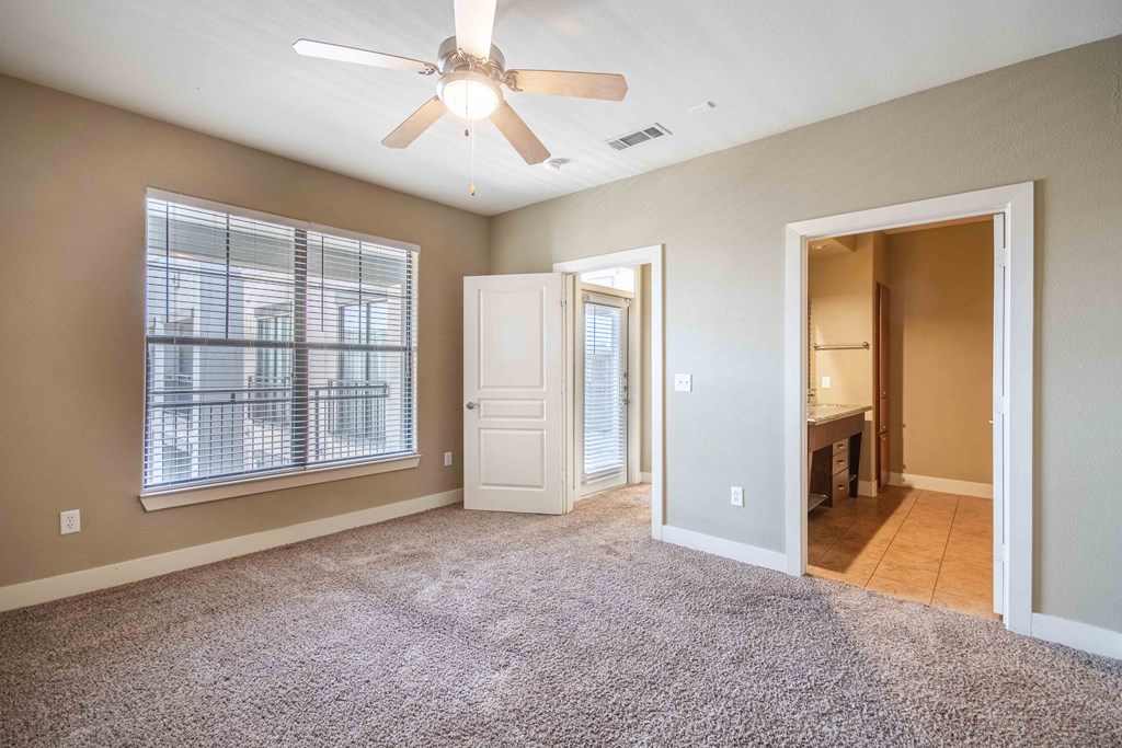 a bedroom with a ceiling fan and a door leading to a bathroom At Metropolitan Apartments in Little Rock, AR