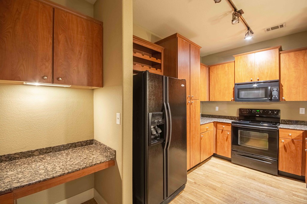 Kitchen with wood flooring and black appliances and wood cabinets and steel sink and shelves