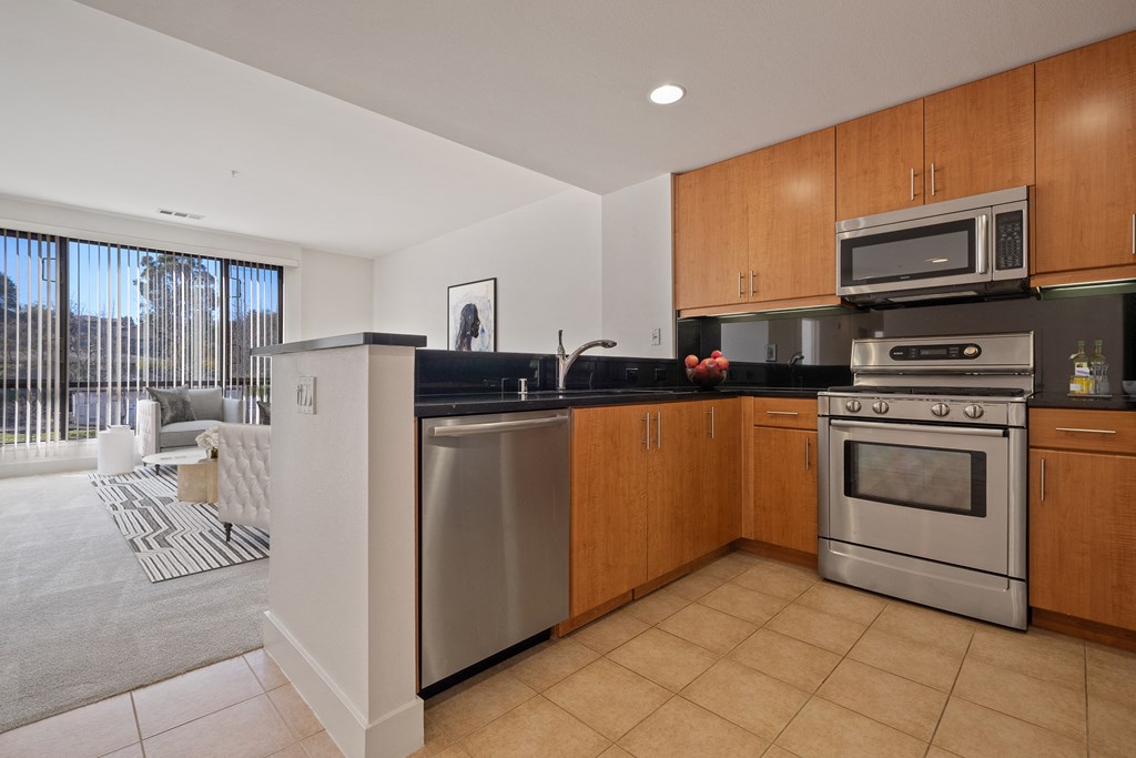 Novato, CA, Pet-Friendly Apartments - Millworks - Kitchen with Tile-Inspired Flooring, Stainless Steel Appliances, Dishwasher, Built-In Microwave, and Wood-Tone Cabinets