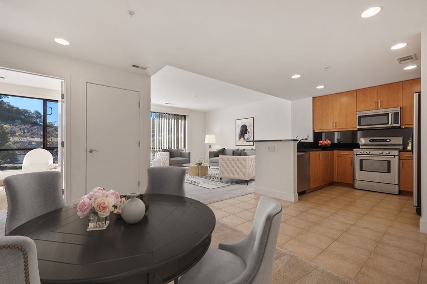 a dining room with a black table and chairs and a kitchen with