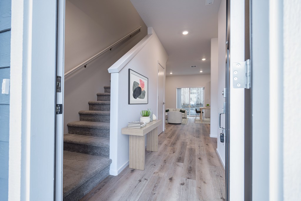 A hallway with a staircase and a painting on the wall.