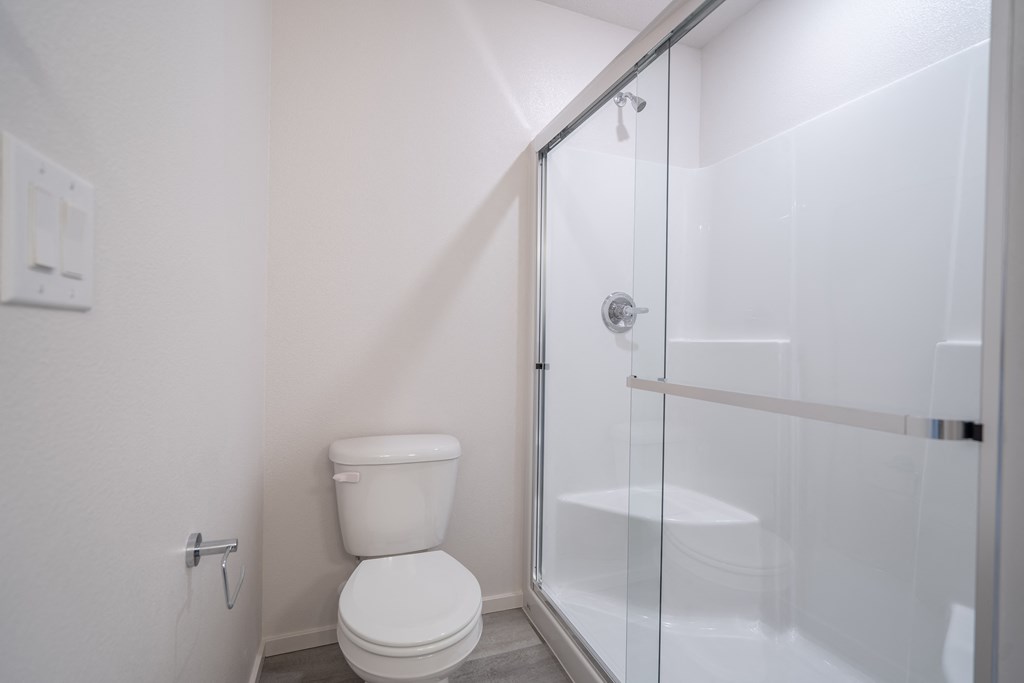 a bathroom with a toilet and a shower with a glass door