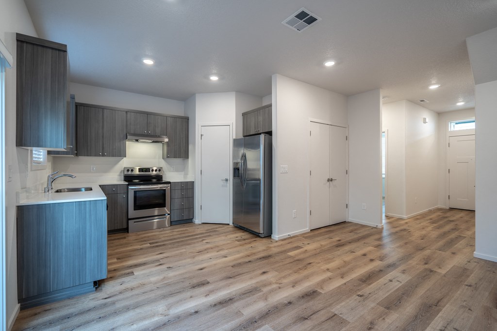 a kitchen and living room with white walls and a wooden floor