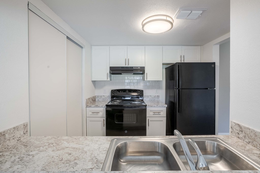 A kitchen with a black refrigerator, stove, and oven.