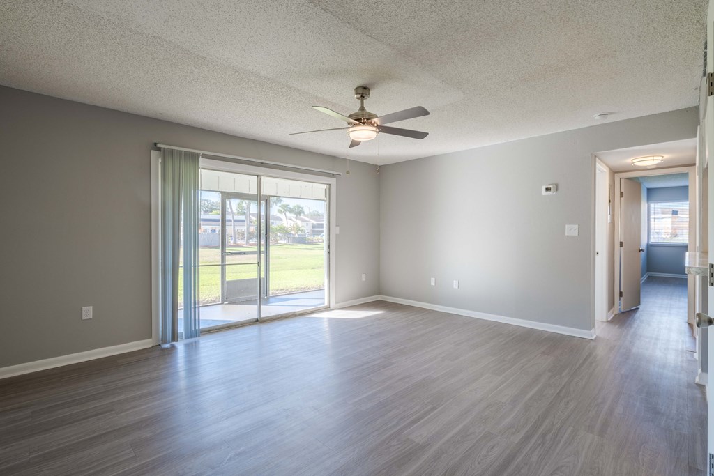 A room with a ceiling fan and sliding glass doors.