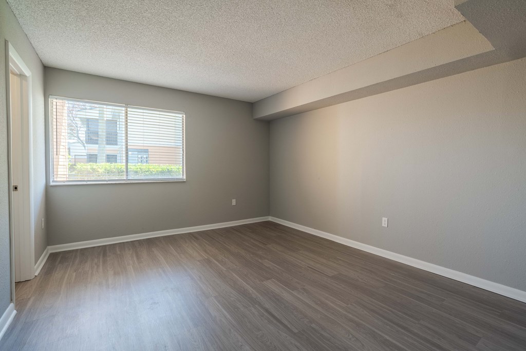 A room with a window and wooden flooring.