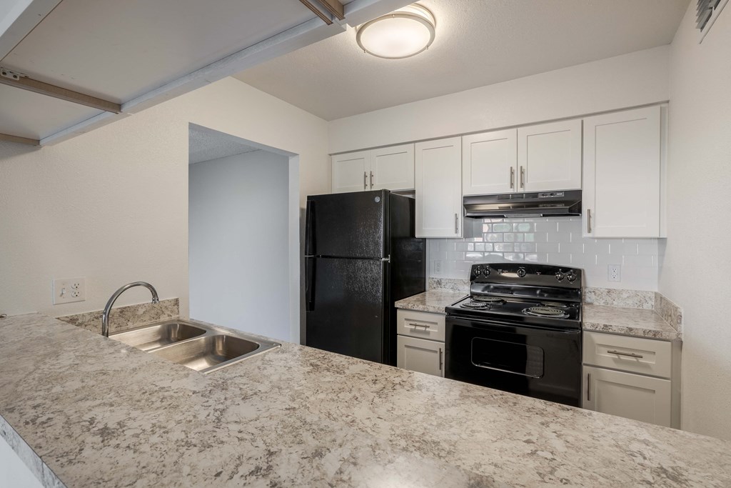 A kitchen with granite countertops and white cabinets.