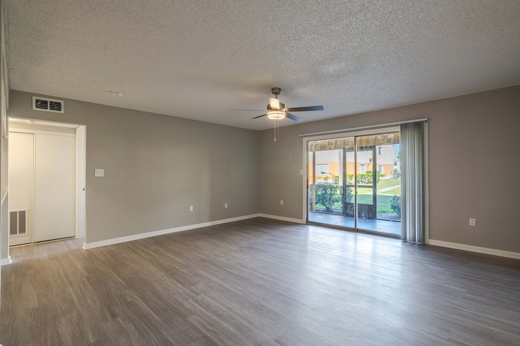 A spacious room with a ceiling fan and sliding glass doors.