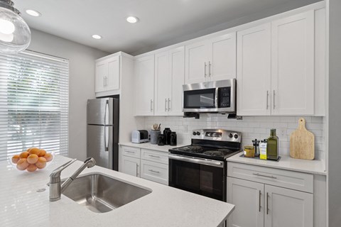 A modern kitchen with white cabinets and stainless steel appliances.